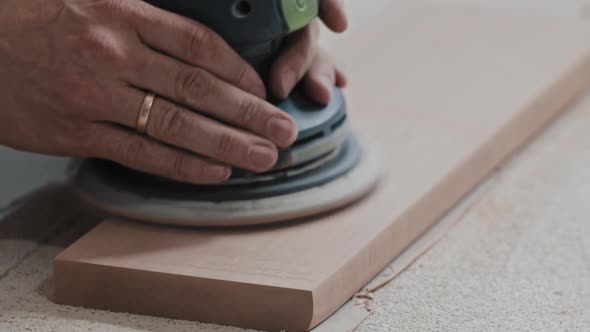 Carpentry Works  Worker Makes the Top Surface of a Wooden Detail Softer with a Grinding Machine