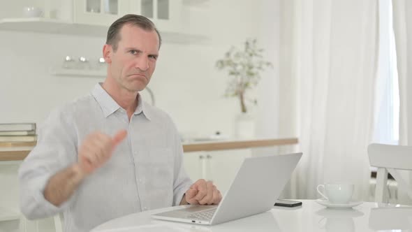 Upset Middle Aged Man with Laptop Doing Thumbs Down