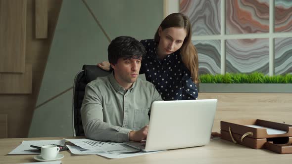 Young Business Partners are Using a Laptop Discussing Documents and Smiling While Working in Office