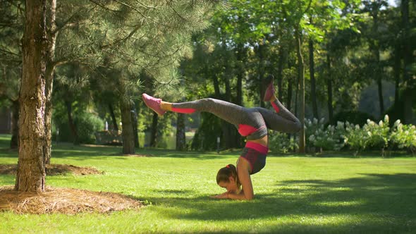Sporty Slim Woman Doing Handstand Exercise on Grass