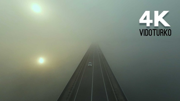 Bridge and river under heavy fog at sunrise