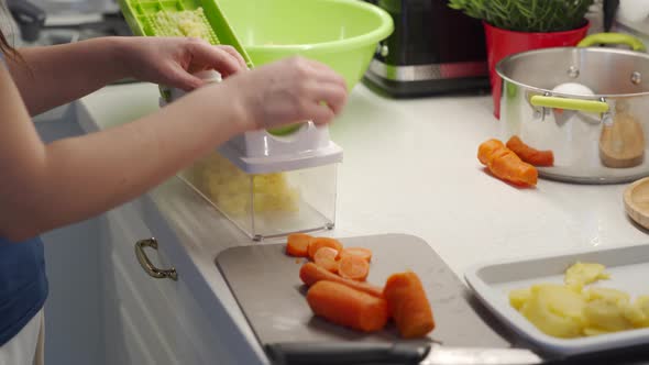 Woman Cooking Salad in the Kitchen Using a Vegetable Chopper with Container Chop and Slice Boiled