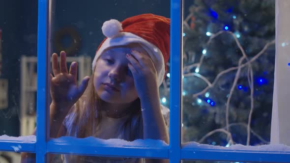 Charming Girl Through Window in Santa Hat