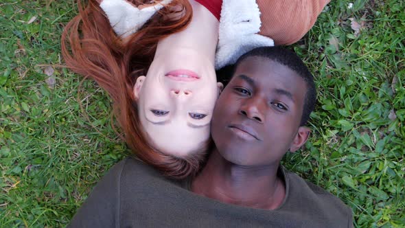 Carefree beautiful young interracial couple lying on the grass