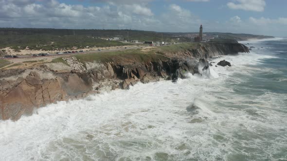 Aerial of rocky cliffs with big waves coming from the sea hitting rocks
