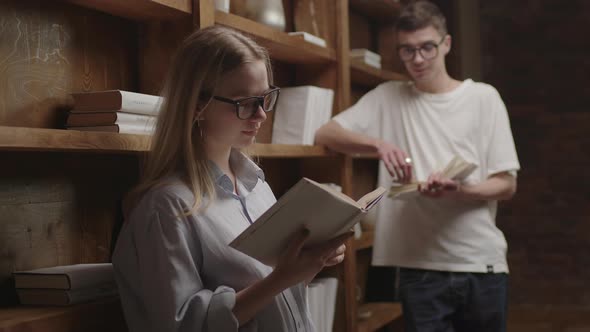 Young Smart Couple in Eyeglasses Reading Books at the Library