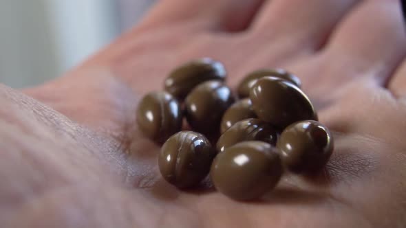 Brown oval medical capsule pills fall into the palm of the hand