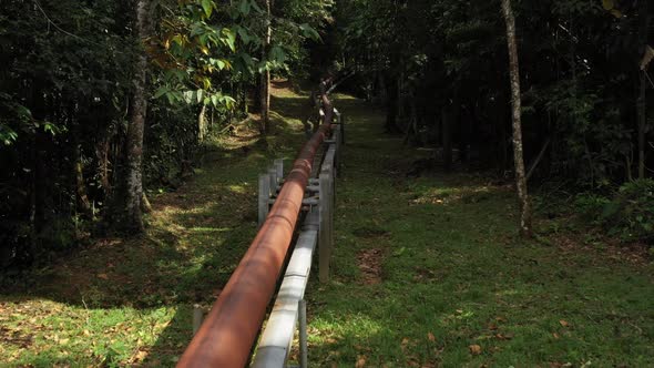 Flying over a rusted brown red oil pipe in the amazon rain forest