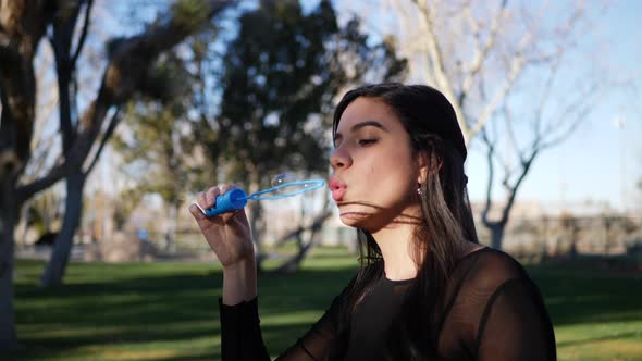 A cute young woman blowing bubbles and frowning in comical failure as they pop in a funny way.