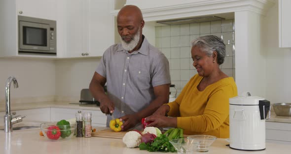 African american senior couple chopping vegetables together in the kitchen at home