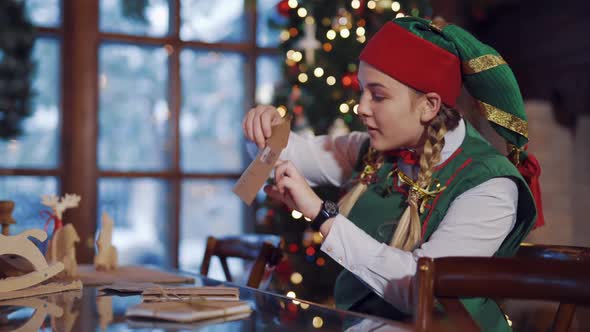 Curious elf looking inside the envelope for Santa.