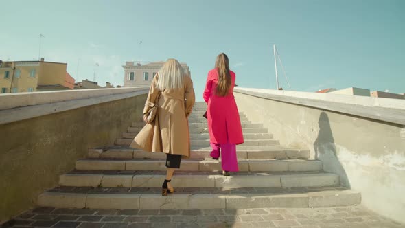 Young Women Friends in Fashionable Outfits Walk Bridge Steps