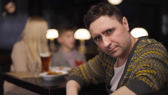 Sad Caucasian Man Sighing Looking at Camera Sitting in Restaurant with Woman and Boy