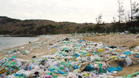 Aerial dolly left shot of plastic rubbish over beach sand, Vietnam