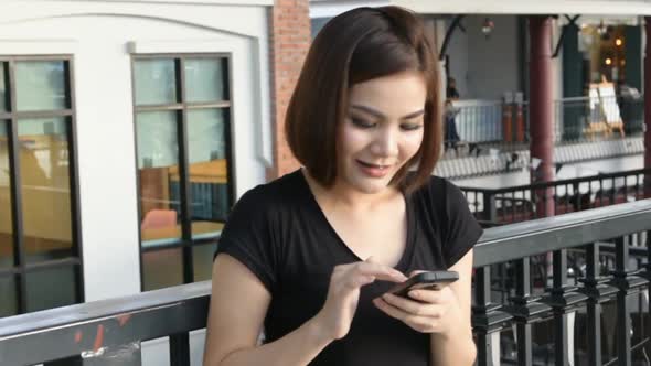 Asian beautiful happy smiling woman using smart phone on cityscape