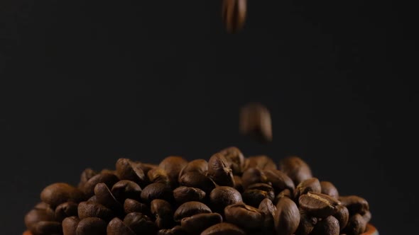 Slow motion of roasted coffee beans falling. Organic coffee seeds.