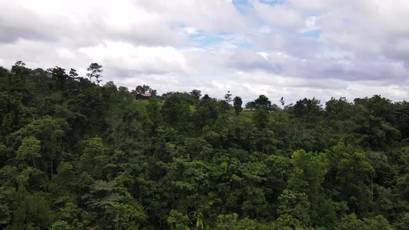 Drone circling around a small building sitting on top of a hill in deep central American rainforest.