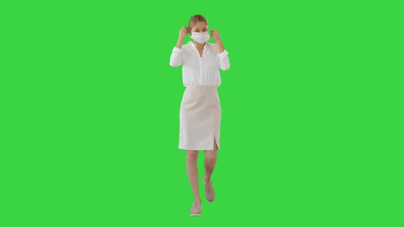 Beautiful Blonde Caucasian Woman Putting Protective Mask On While Walking on a Green Screen, Chroma