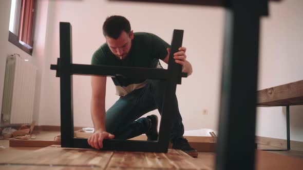 Assembling DIY Table. Man Installing Modern Metal Table Leg To Wooden Table Top. static