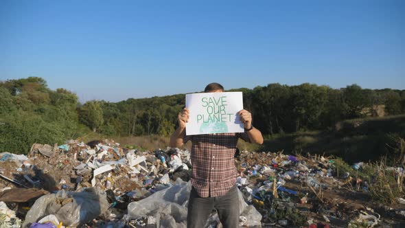 Male Eco Activist in Protective Mask Looks Into Camera Holding in Hands Banner of Environmental