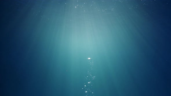 Sunlight beams shining through the deep crystal clear blue-turquoise colored water causing a beautif