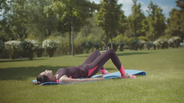 Spory Female Exercising on Fitness Mat in Park