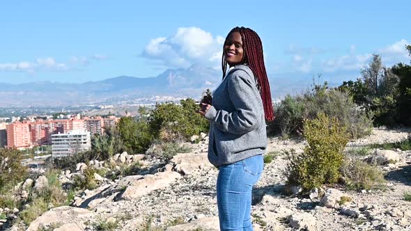 African Woman with Dreadlocks is Dancing Against Mountain and Sky