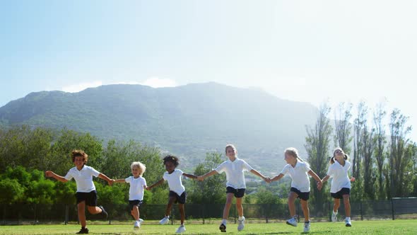 School kids holding hands and running in park