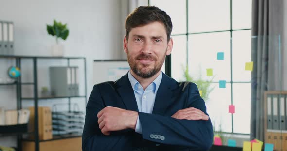 Businessman in Suit which Looking Into Camera with Crossed Arms on the Modern Office Room