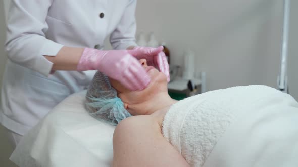 Woman Lying on Spa Bed Receiving Face Massage with Skin Care with Aromatic Essential Oil From