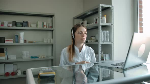 Woman Pharmacy Seller in Headset with Laptop Talking with Customer Online