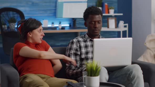 Interracial Couple Expecting Child Sitting Together on Couch