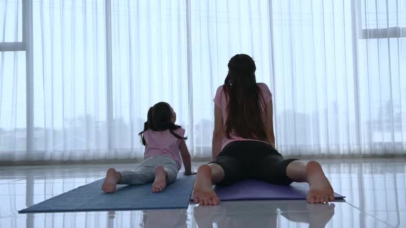 Mother and daughter exercises with yoga activity in the living room of the house.