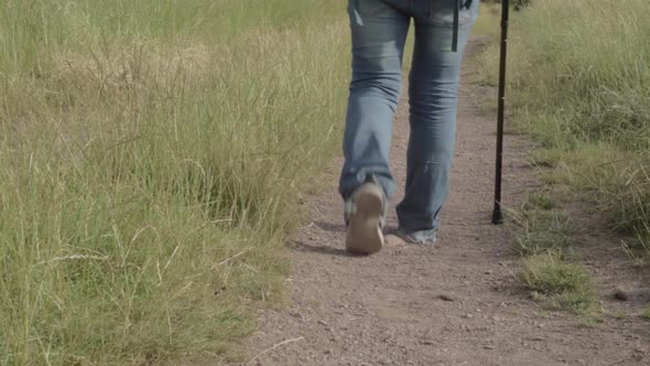 Hiker on dusty countryside path with walking stick