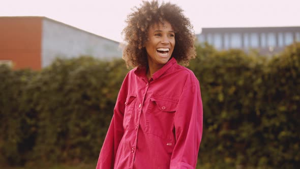 Young Woman With Afro Hair Laughing In Pink Clothes