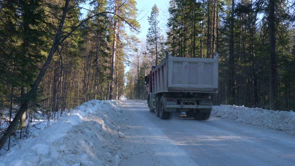 A Truck Carrying Ore Rides Along a Winter Forest