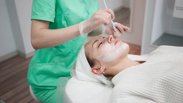 Female Beautician Makes Face Rejuvenation and Cleansing Procedure for Girl