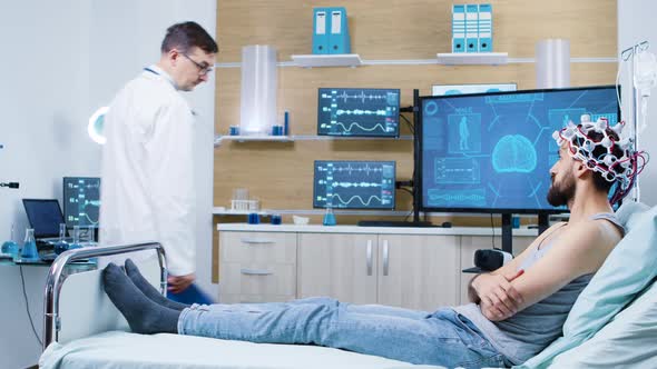 Doctor in a Brain Research Laboratory Checking on Patient Sitting on Bed