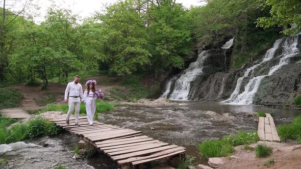 Romantic couple with lilac flowers walking and sightseeing near waterfall.