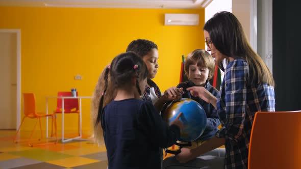 Diverse Kids and Teacher with Globe in Kindergarten