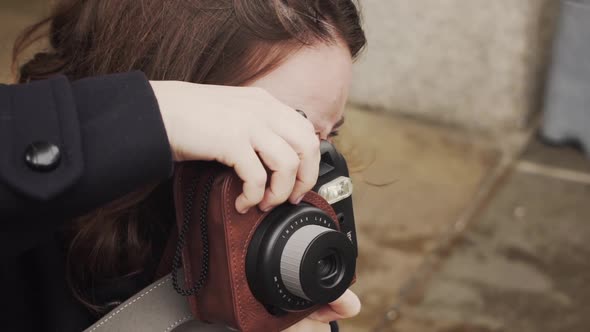 Young Caucasian brunette woman taking photograph outside with camera, close up slow motion