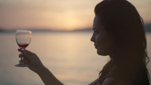 Romantic Girl with a Glass of Wine on the Beach Near the Ocean