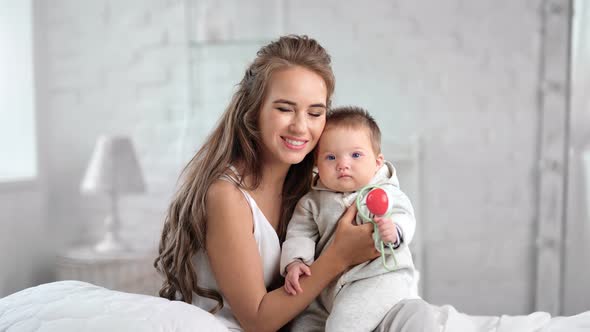 Young Beautiful Mother Hugging and Kissing Her Little Baby Having Positive Emotion Feeling Love