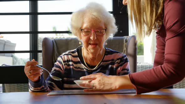 Daughter serving soup to her mother on dining table 4k