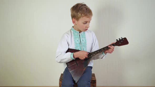 Russian Boy in National Dress Plays the Balalaika.