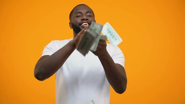 Happy African-American Man Throwing Dollars Banknotes, Wasting Money, Concept