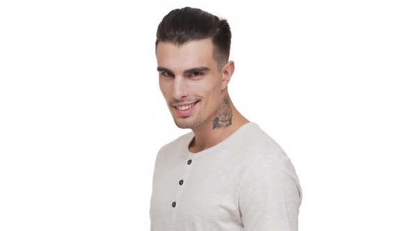 Halfturn Portrait of Handsome Smiling Guy with Bristle and Tattoo on Neck Posing on Camera with