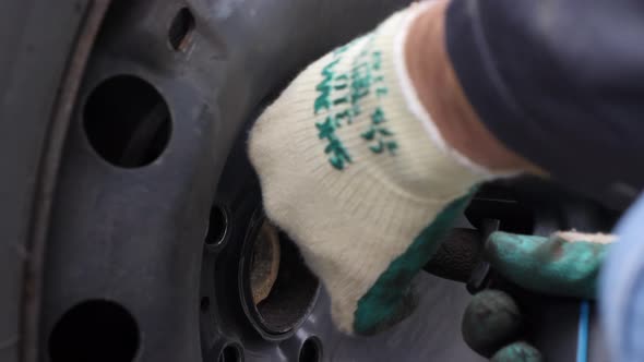 Extreme close up, mechanic unscrews a winter tire with an electric impact wrench