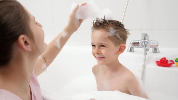 Happy Smiling Mother with Son Playing in Bathroom and Making Stylish Haircuts with Soap Foam