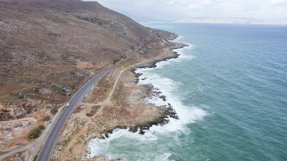 Epic aerial drone shot of coastline highway еraffic along cinematic winding mountain road